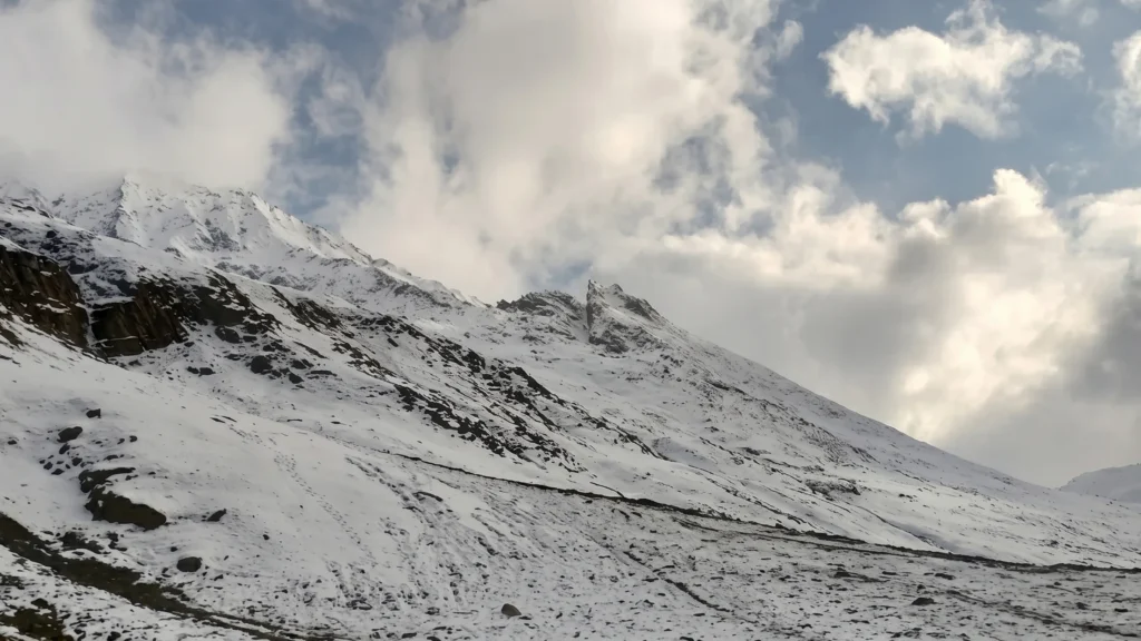 Snow-covered slopes of Thajiwas Glacier near Sonamarg under a cloudy sky, showing early-season winter conditions.